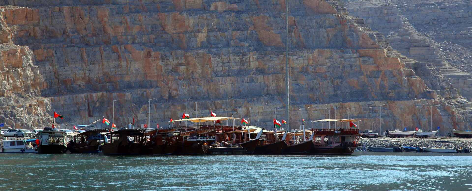 Traditional dhow boats moored below the cliffs of Musandam, Oman | nomad