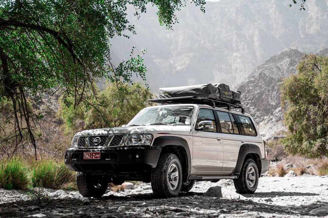 Nissan Patrol rooftop tent vehicle on a mountain track during a self-drive Oman road trip | nomad